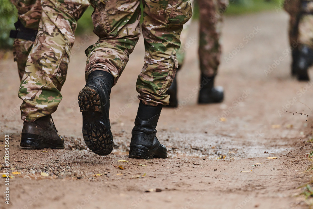 Close up photo, the resilient legs of elite soldiers, clad in camouflage boots, stride purposefully along a hazardous forest path as they embark on a high-stakes military mission Close up photo, the resilient legs of elite soldiers, clad in camouflage boots, stride purposefully along a hazardous forest path as they embark on a high-stakes military mission