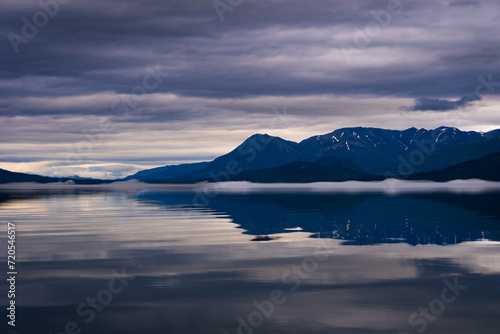 Lake Clark in Lake Clark National Park and Preserve in Alaska. Turquoise lake with rugged mountains  islands and shore. Dena  ina  Qizhjeh Vena. Pink and purple reflections on foggy lake.