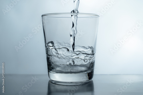 pouring water into glass on table, glass of water with splash isolated on white background. clean water for a good health. Mineral water in glass. 