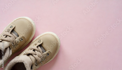 New warm waterproof winter boots on light pink table background. Pastel color. Children footwear. Closeup. Empty place for text. Top down view.