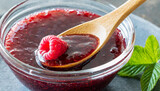 raspberry jam is stirred with a wooden spoon.