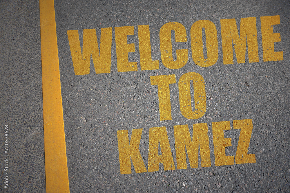 asphalt road with text welcome to Kamez near yellow line.
