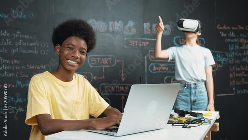 Smart african student programming and coding innovative system while caucasian girl enter in metaverse or virtual world by using VR or head set at blackboard in STEM technology classroom. Edification photo