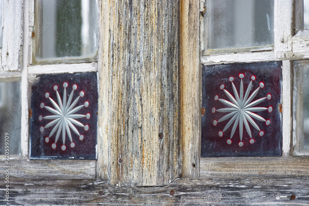 Snowflakes in a glass window as a decorative element, windows of a wooden old cottage from the early 20th century.