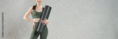 Fotografie Unrecognizable female athlete posing, while holding dark mat for yoga practice