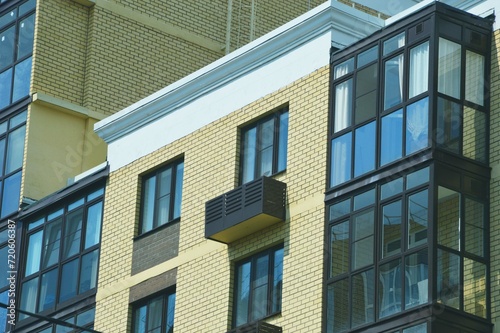 Multi-apartment urban residential building. Element of the facade of a brick building with glass windows and loggias.