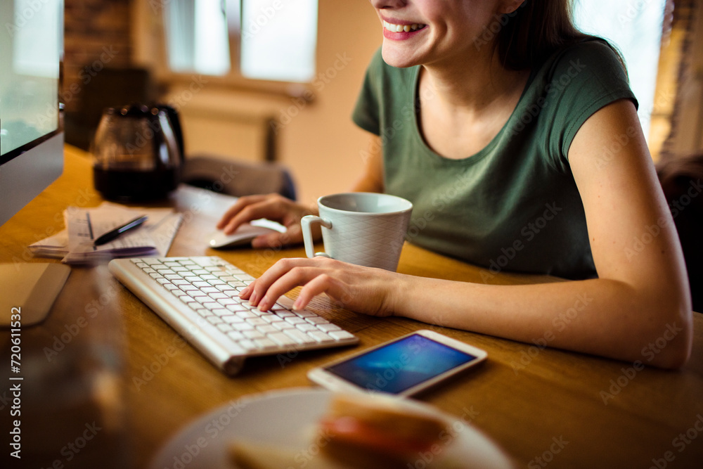 Freelancer working on computer with breakfast sandwich on desk Freelancer working on computer with breakfast sandwich on desk