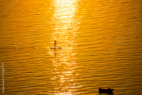 Standup paddleboarder woman at sunset in Lake Balaton photo