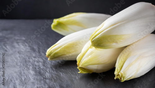 Fresh raw Belgian endives (chicory) on black table, closeup, copyspace on side