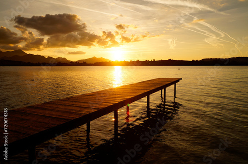 a long pier at Forggensee lake in the Bavarian Alps at romatic sunset on a sunny September evening