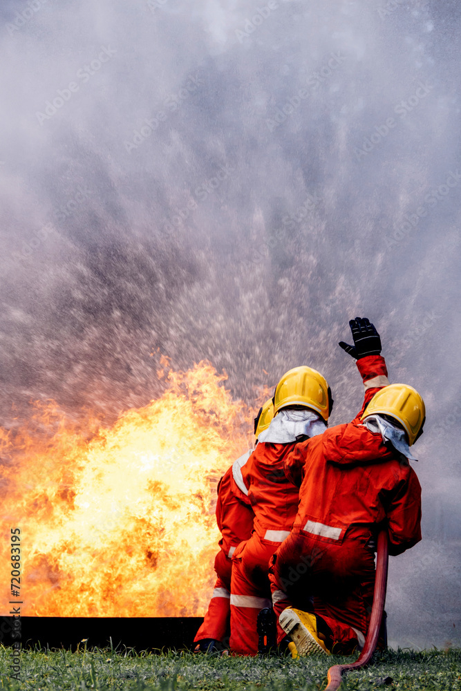 Fototapeta premium Firefighter Concept. Several firefighters go offensive for a fire attack. Fireman using water and extinguisher to fighting with fire flame.