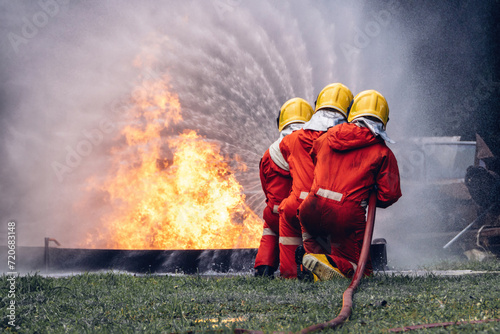 Firefighter Concept. Several firefighters go offensive for a fire attack. Fireman using water and extinguisher to fighting with fire flame.