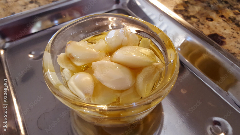 Garlic cloves in boiling olive oil - glass cup in oven Garlic cloves in boiling olive oil - glass cup in oven