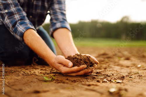 Male hands touching soil on the field. Expert hand of farmer checking soil health before growth a seed of vegetable or plant seedling. Concept of agriculture, business and ecology.