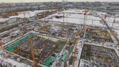 Several cranes work on large building site in city at winter day photo