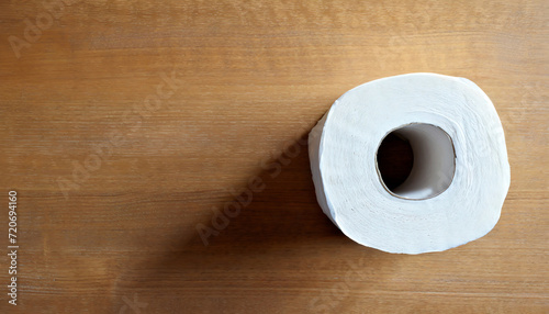 Top view of a roll of toilet paper standing on a wooden floor