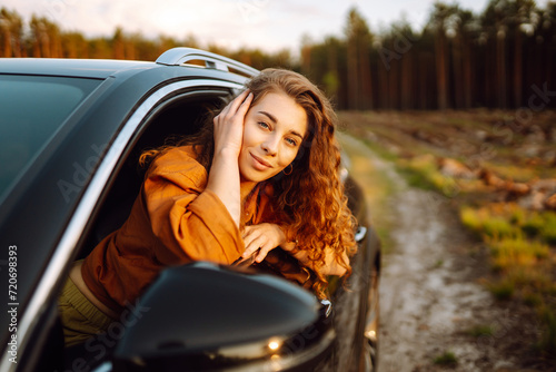 Young woman leaning out of the car window enjoying nature. Lifestyle, travel, tourism, active life.