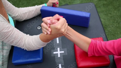 Girl and woman are fighting in arm-wrestling on a table photo