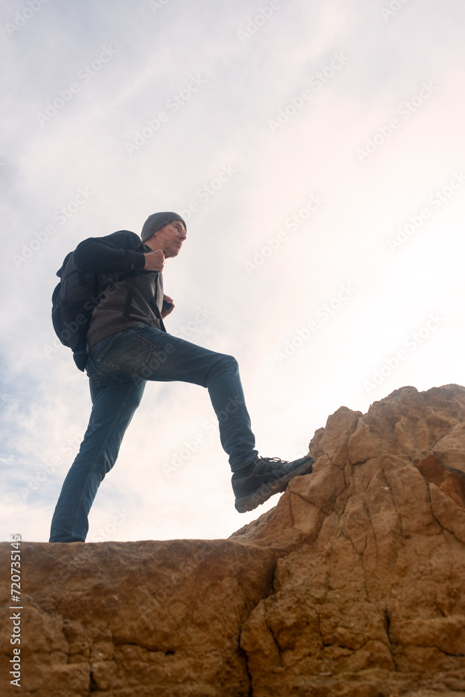 male hiker with backpack walking over rocks, climbing up. male hiker with backpack walking over rocks, climbing up.