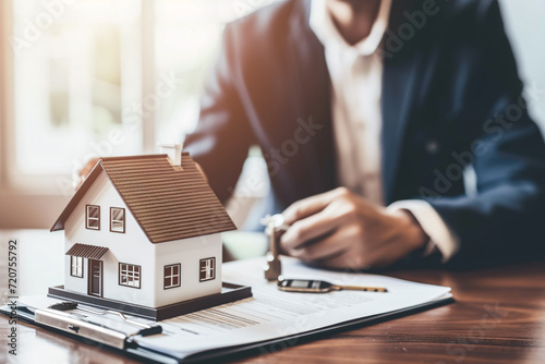 Homeownership concept, a realtor with a house key, a model house, and a contract, buying a home