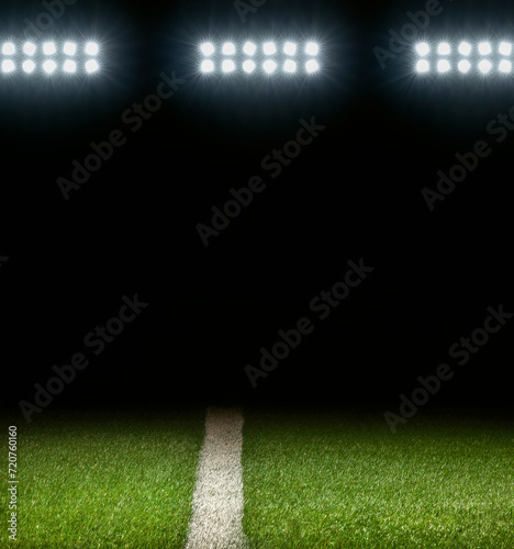 Grass athletic field with white stripe and dark background below stadium lights