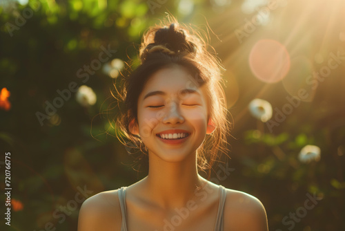 Close-up portrait of a young Asian womans face, sunlit with a gentle smile. Nature beauty. Concept of naivety and purity photo