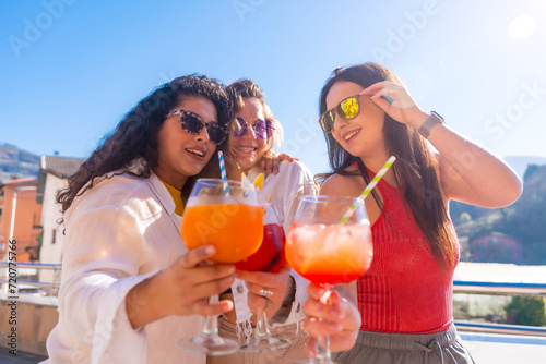 Cool women toasting with cocktails in a terrace in summer