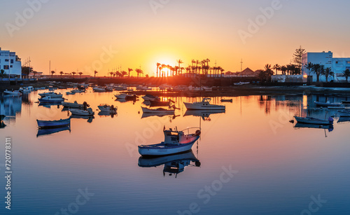 Lanzarote sunrise over Arrecife featuring a lone boat on calm waters. The capital's coastal creating a tranquil scene on Charco de San Gines lake. photo