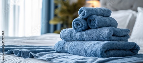 A cozy indoor bed adorned with a stack of soft blue linens, including towels, cloths, and blankets, invites relaxation and comfort photo