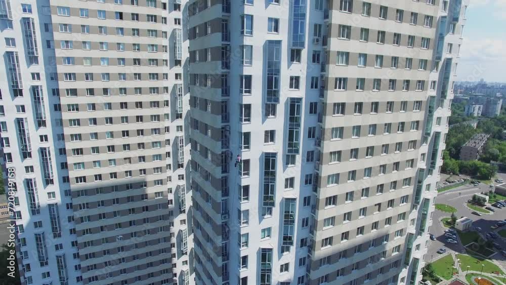 Exterior of tall dwelling house with mountaineer which hangs on rope