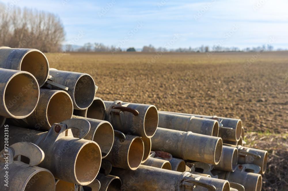 Guiding the Water: Close-up of Irrigation Pipes with Plowed Field in the Background. Guiding the Water: Close-up of Irrigation Pipes with Plowed Field in the Background.