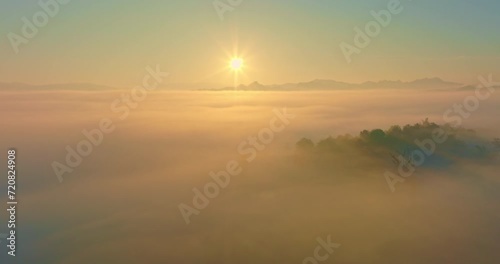 Aerial view above the sea of mist at beautiful sunrise..slow floating fog blowing cover on the top of mountain look like as a sea of mist. .white cloud in blue sky over the perfect forest. photo