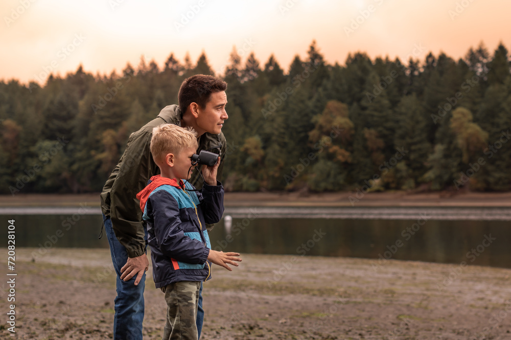 Obraz premium Father and son outdoors family adventure discovering nature together looking at wildlife with binoculars 