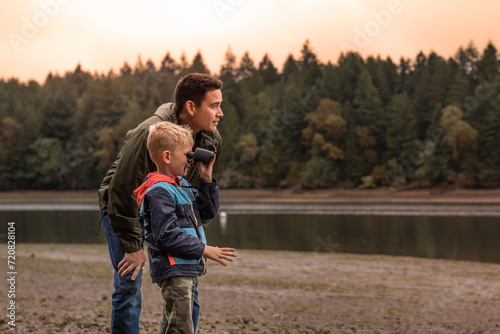 Father and son outdoors family adventure discovering nature together looking at wildlife with binoculars  