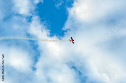 Pilot in a single-engine, or turbo-prop, display plane doing maneuvers and streaking the sky and clouds in the background