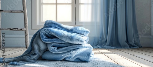 A pile of crisp blue towels rest on the ground, beckoning for a cozy indoor escape by the window