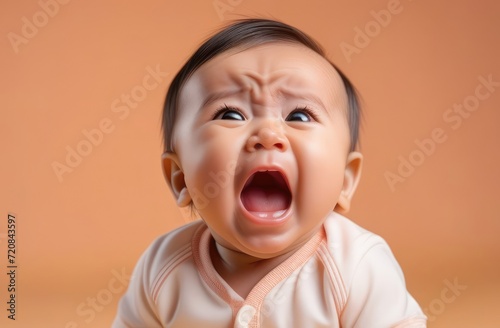 little Asian toddler boy crying out loud on beige background, closeup. providing tender baby care