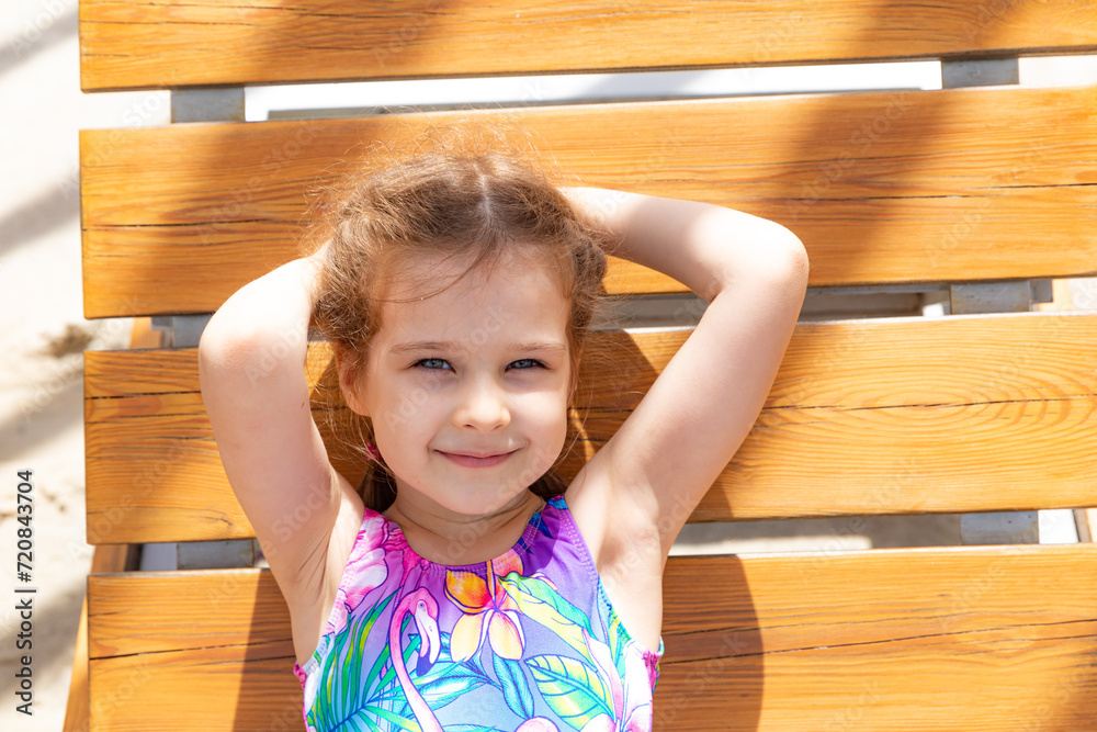 Cute adorable caucasian little kid girl enjoy having fun relaxing on sunbed on a beach. Child chilling outdoor on sunny day Cute adorable caucasian little kid girl enjoy having fun relaxing on sunbed on a beach. Child chilling outdoor on sunny day