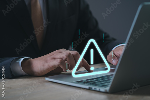 Businessman or User using laptop with problem safety security triangle caution warning sign alarm for notification network error and maintenance concept. warning sign exclamation. photo
