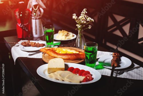 fresh Georgian meal with khachapuri, shashlik kebab with beef or lamb meat, tomato with cheese and green tarragon drink photo