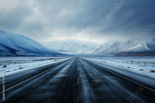 A dynamically blurred road with a sense of speed leading to snowy mountains.