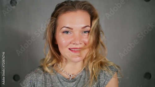 Blonde girl smiles and poses near wall during photo session photo