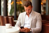 Handsome young businessman using mobile phone in a coffee shop.