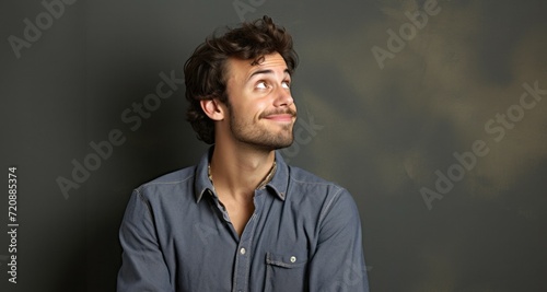 Portrait of a handsome young man in a blue shirt on a dark background © YannTouvay