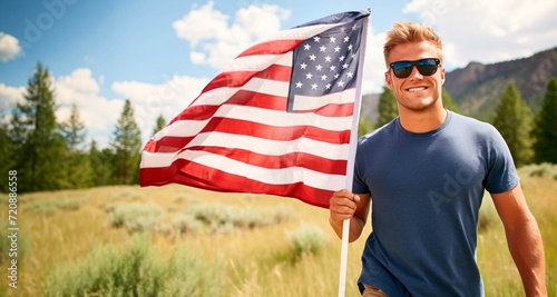 Handsome young man holding an American flag in the field.