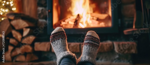 Woman in wool socks warms feet by cozy fire in after ski cabin, closeup of cute legs in cold season. photo