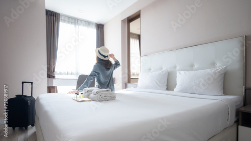 Rear view of tourist woman sitting on bed after arrival at hotel.