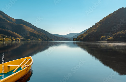 Landscape of a river valley with a yellow boat reflected in the serene waters. Nature travel concept