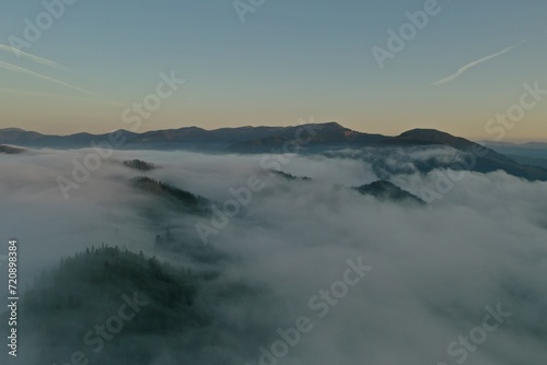 Aerial view of beautiful mountains covered with fluffy clouds in morning