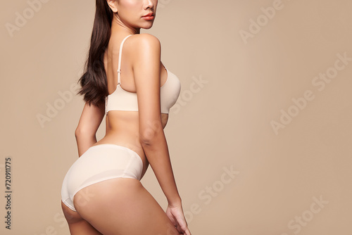 Confident beautiful young asian woman posing in white lingerie on beige background, Perfect body,